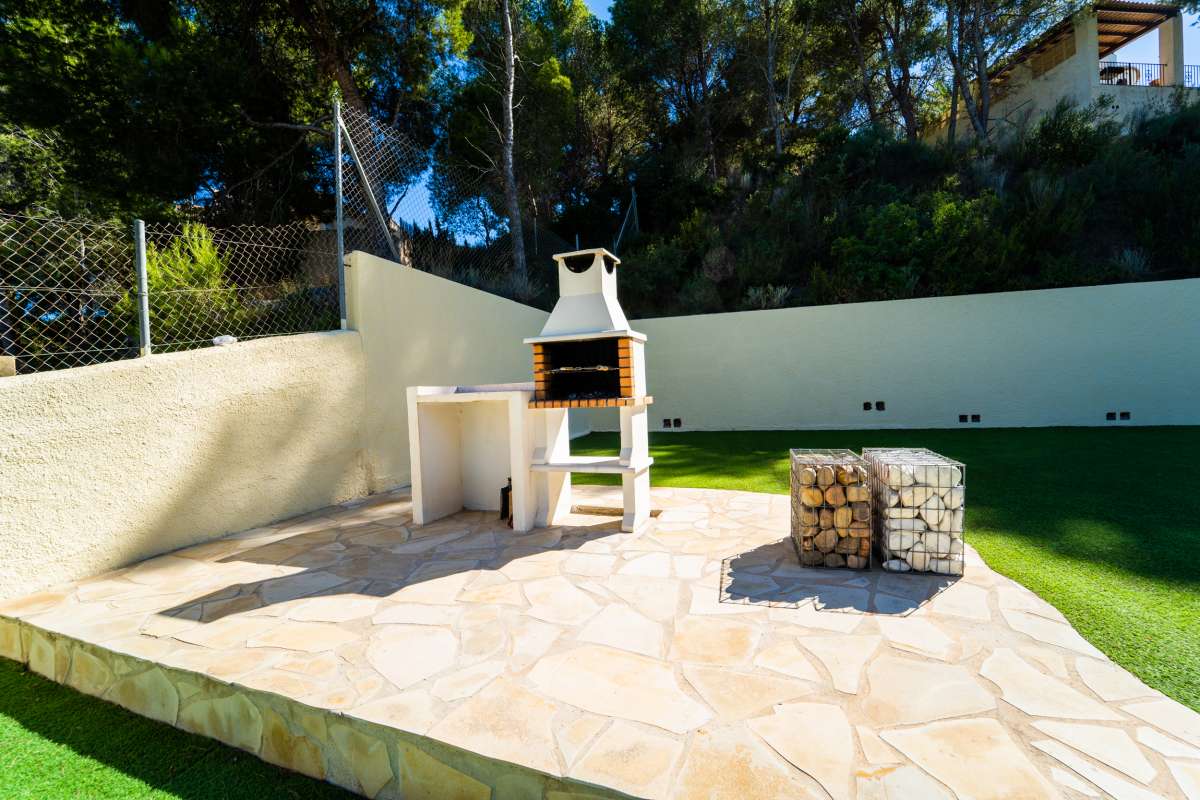 Barbecue terrace with stone table and artificial lawn at a Mediterranean villa in Cometa III, Calpe.