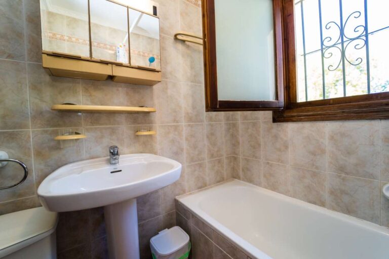 Bathroom detail with bath, sink, shelving and natural light inside a Mediterranean villa in Calpe.