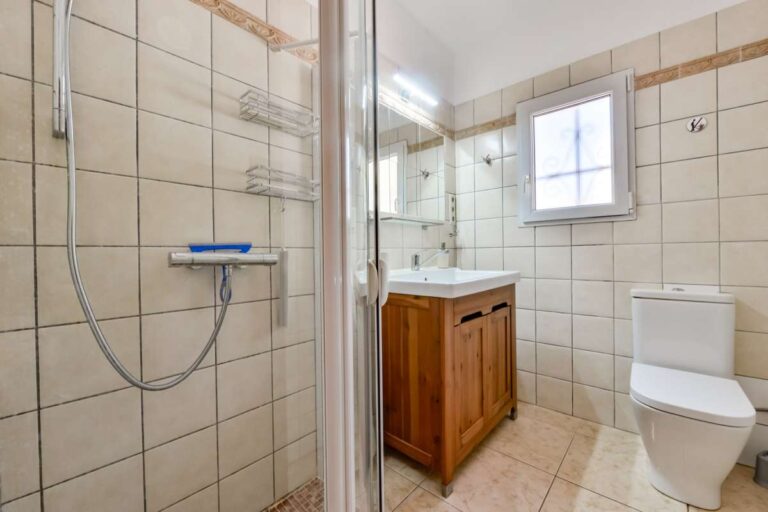 Bathroom inside a charming Benissa Coast villa with shower enclosure, toilet, wooden vanity unit and tiled finish
