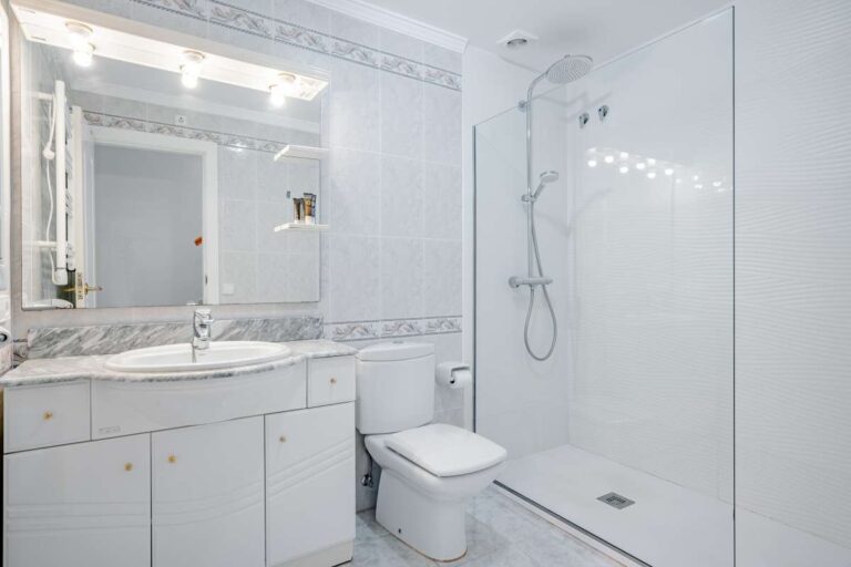 Bathroom inside a duplex apartment near Les Platgetes Beach in Moraira with walk-in shower, vanity unit, toilet and white tiled finish