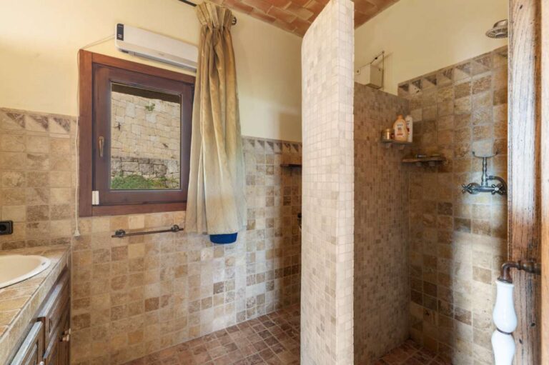 Bathroom inside a finca-style villa in Benissa Costa with walk-in shower, vanity unit, tiled walls, window and rustic Mediterranean design