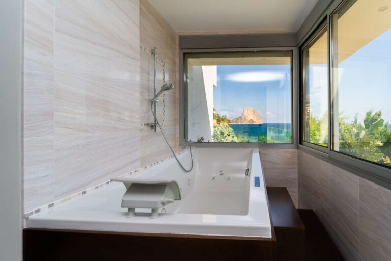 Bathroom inside a luxury villa in Calpe with bathtub, shower, large windows and views towards the Peñón de Ifach and Mediterranean Sea