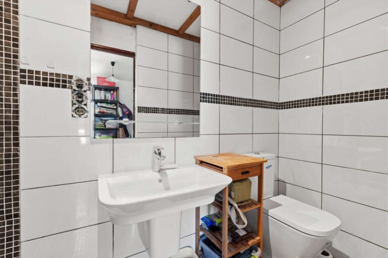 Bathroom inside a Mediterranean villa in Benissa Costa with white tiled walls, basin, toilet and simple functional layout