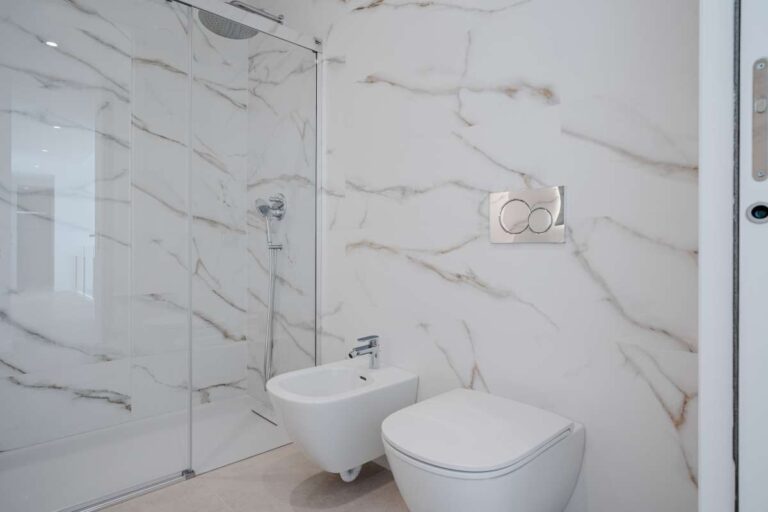 Bathroom inside a modern second-line sea villa in La Calalga, Calpe with marble-effect tiling, bidet, toilet and glass shower screen