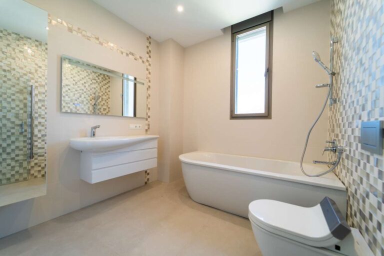 Badezimmer in einer neu gebauten Luxusvilla in der Nähe des Yachthafens Puerto Blanco in Calpe mit freistehender Badewanne, ebenerdiger Dusche, Waschtisch und modernen Fliesen.