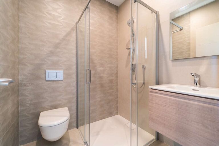 Badezimmer in einer neu gebauten Luxusvilla in der Nähe des Yachthafens Puerto Blanco in Calpe mit Glasduschkabine, wandhängendem WC, Waschtisch und modernen Fliesen.