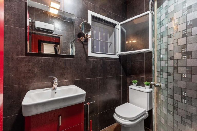 Bathroom inside a panoramic sea view villa in Benissa with dark tiled finish, vanity unit, toilet and glass shower screen
