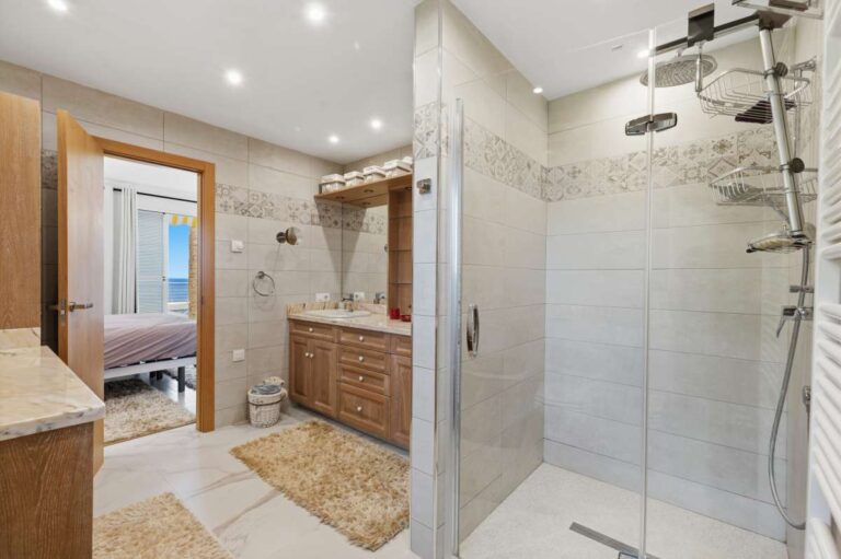 Bathroom inside a premium coastal villa on the Benissa Costa with walk-in shower, wooden vanity unit, toilet and bright tiled finish