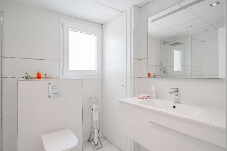 Bathroom inside a renovated apartment in Arenal-Bol, Calpe with vanity unit, toilet and bright white modern finish