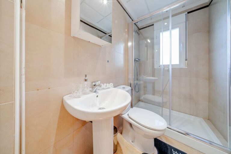 Bathroom inside a semi-detached house in Calpe with shower enclosure, sink, toilet and natural light