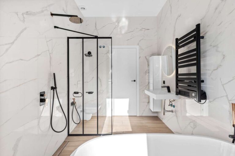 Bathroom inside a single-level modern villa in Santa Clara, Altea with walk-in shower, bath, black fittings, towel rail and marble-effect walls