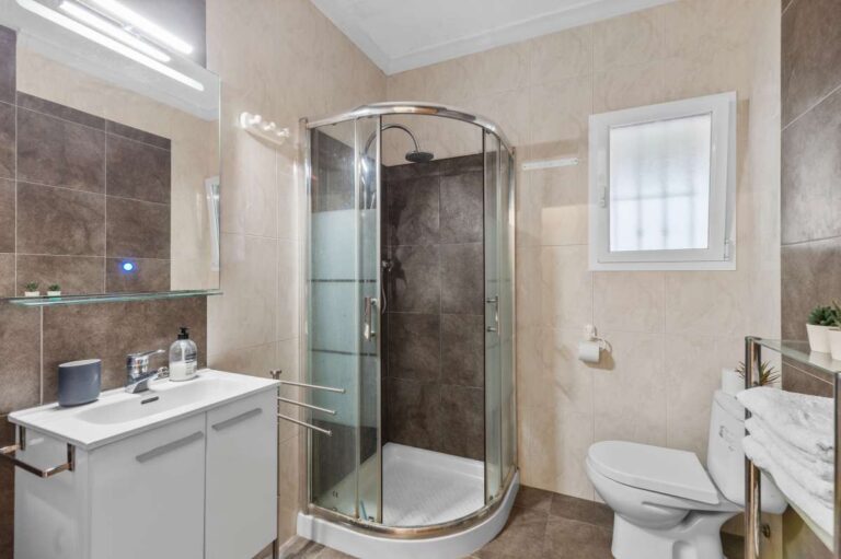 Bathroom inside an independent apartment of a Benissa sea view villa with corner shower, vanity unit, toilet and bright tiled finish