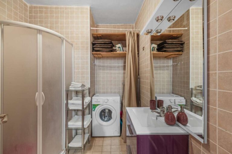 Bathroom inside an independent apartment of a Benissa sea view villa with shower, vanity unit, washing machine and storage shelves