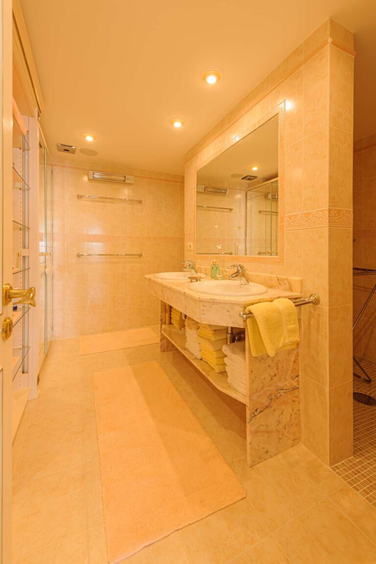 Bathroom vanity area inside a luxury apartment in Sierra de Altea with large mirror, marble-style finish, built-in storage and bright lighting