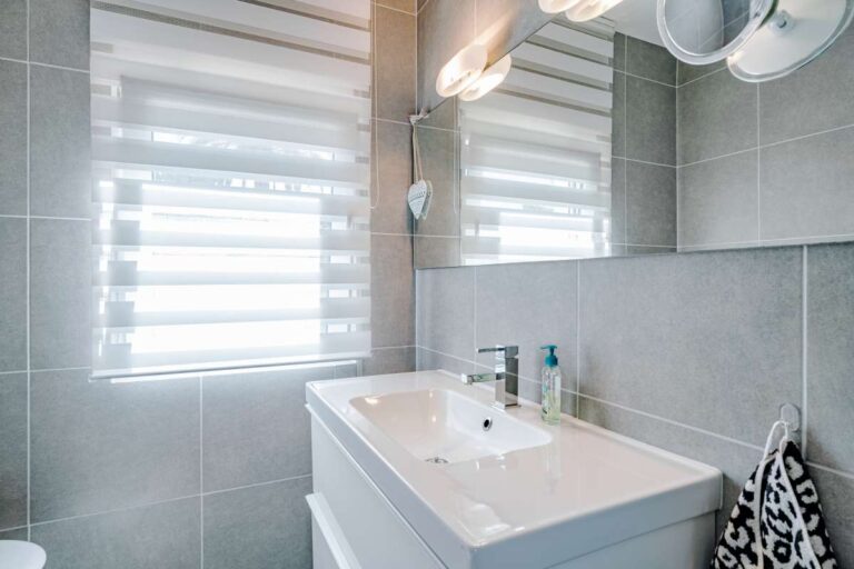 Bathroom vanity area inside a modern villa in Calpe with mirror, sink unit and tiled walls