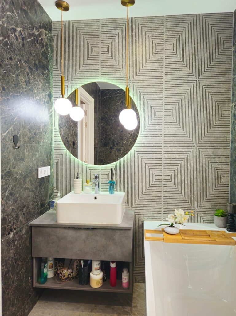 Bathroom vanity area inside a modern villa near Les Bassetes, Calpe with round mirror, tiled walls and built-in storage