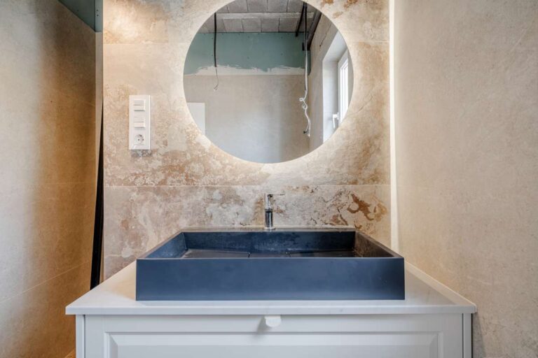 Bathroom vanity with round mirror and modern wall tiles inside a new build villa near the coast in Calpe