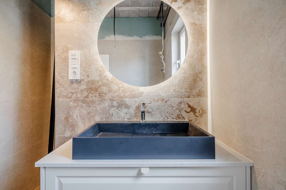 Bathroom vanity with round mirror and modern wall tiles inside a new build villa near the coast in Calpe