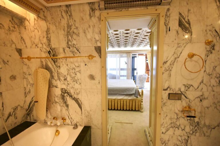 Bathroom with bath, marble-style finishes and view towards the glazed terrace inside a frontline double penthouse in Calpe.