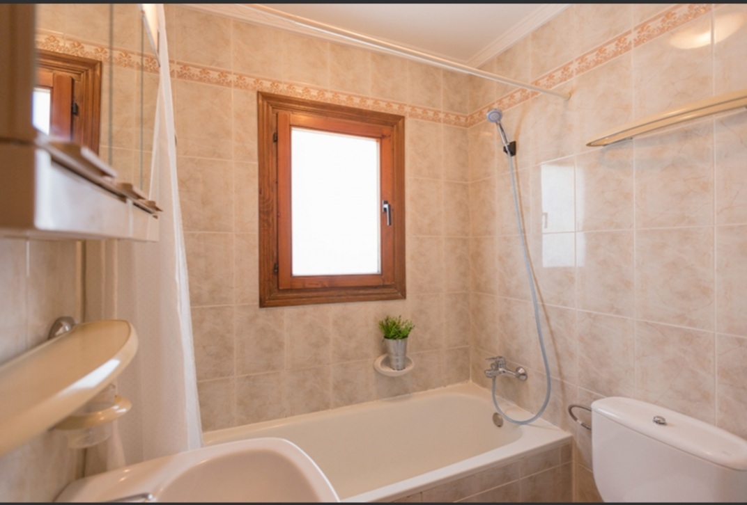 Bathroom with bath, shower fitting and natural light inside a Mediterranean villa in Calpe.