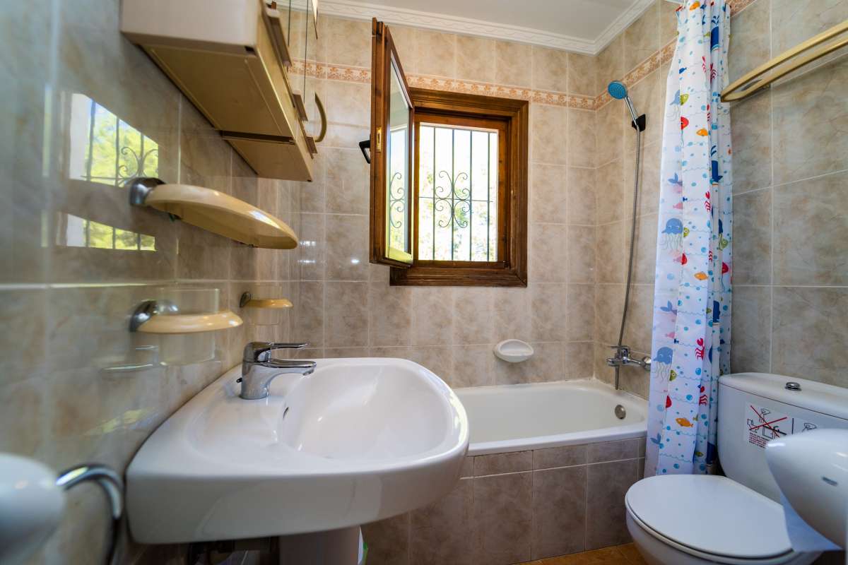 Bathroom with bath, sink and natural light inside a Mediterranean villa in Cometa III, Calpe.