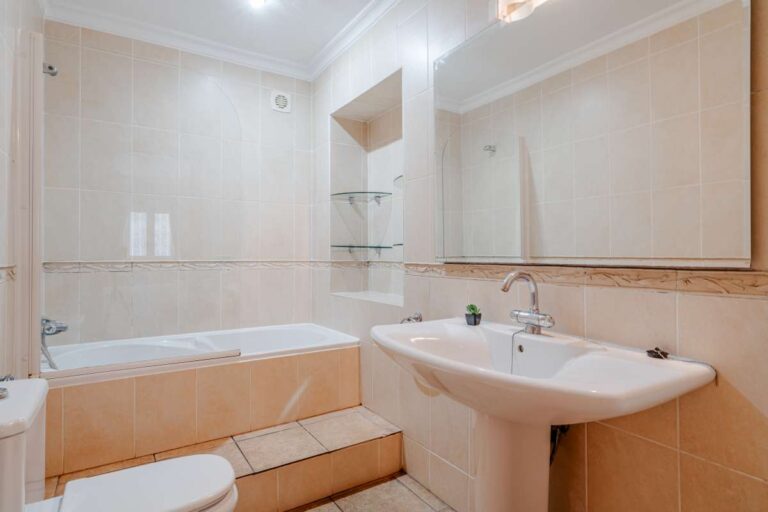 Bathroom with bath, sink and tiled walls inside a Mediterranean villa with independent guest accommodation in Calpe.
