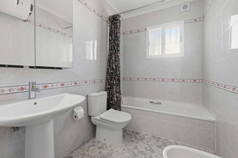 Bathroom with bath, sink, toilet, and natural light inside a villa in Calpe.