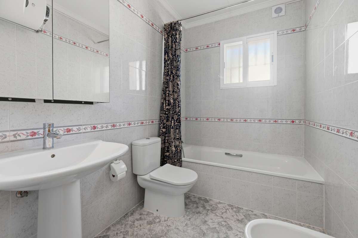 Bathroom with bath, sink, toilet, and natural light inside a villa in Calpe.