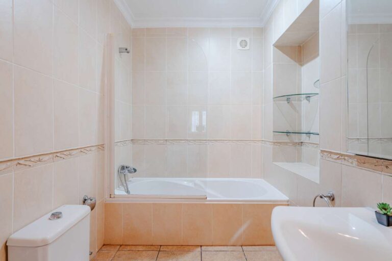 Bathroom with bath, toilet and tiled walls inside a Mediterranean villa with independent guest accommodation in Calpe.