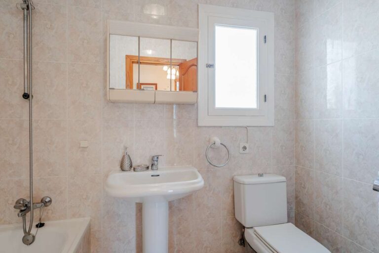 Bathroom with bath, toilet, sink and natural light inside a Mediterranean villa in Calpe.
