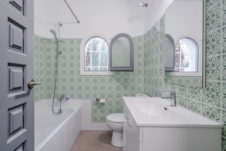 Bathroom with bath, vanity and green patterned tiles inside an independent apartment at a Mediterranean villa in Maryvilla, Calpe.