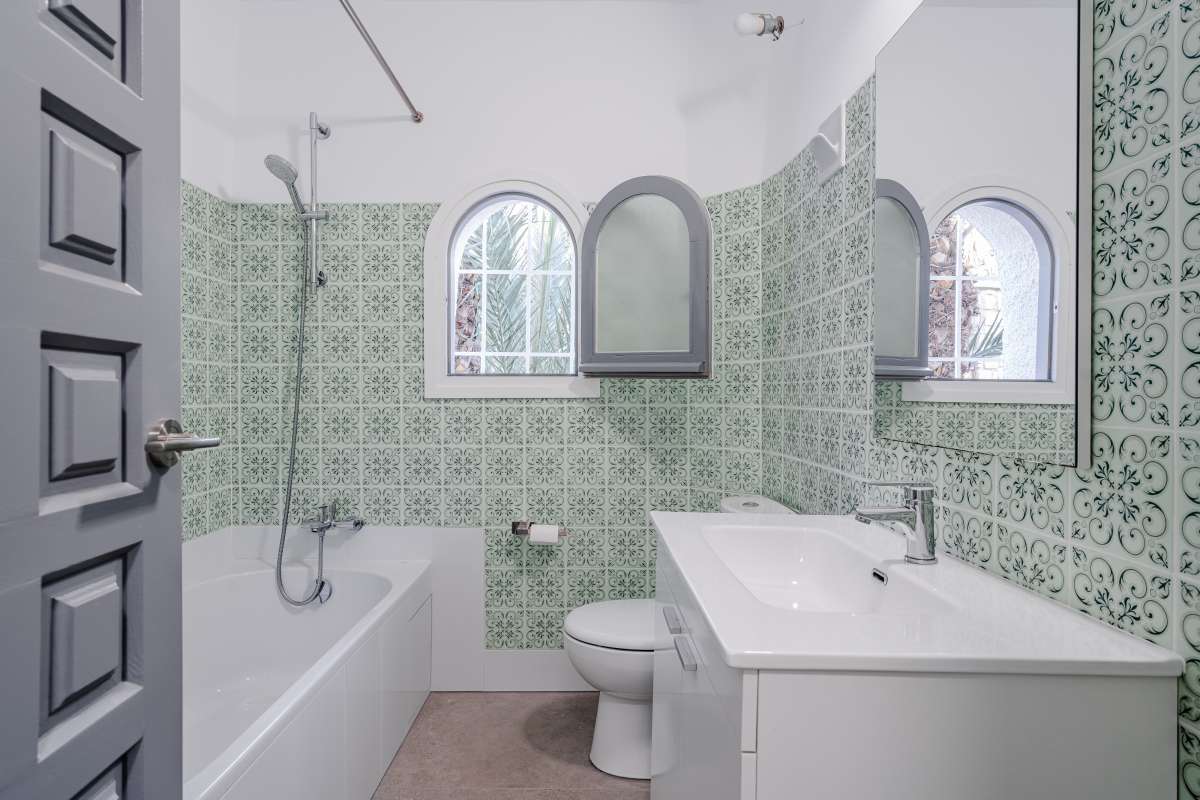 Bathroom with bath, vanity and green patterned tiles inside an independent apartment at a Mediterranean villa in Maryvilla, Calpe.
