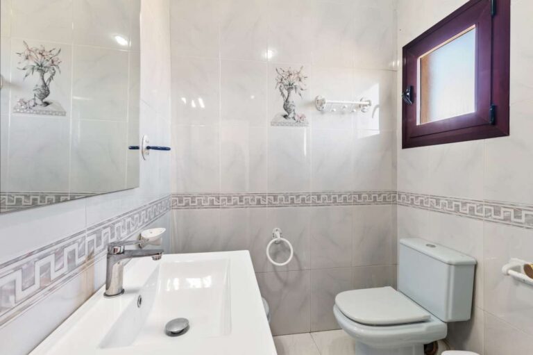 Bathroom with bathtub, toilet and natural light inside a guest apartment at a spacious villa in Calpe.