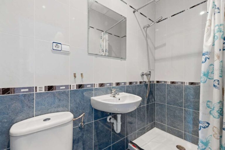 Bathroom with blue tiles, sink, toilet, and shower inside a villa in Calpe.