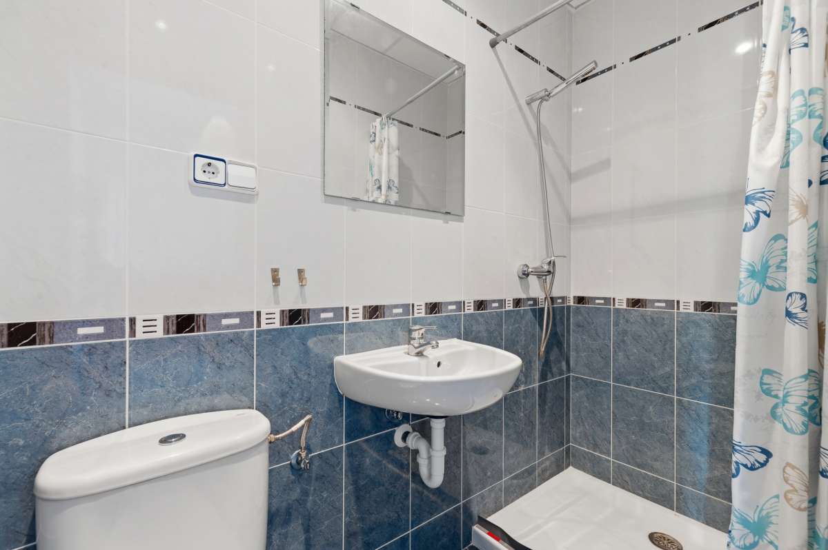 Bathroom with blue tiles, sink, toilet, and shower inside a villa in Calpe.