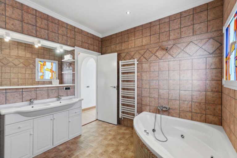 Bathroom with corner bath, vanity, and tiled walls inside a villa in Calpe.