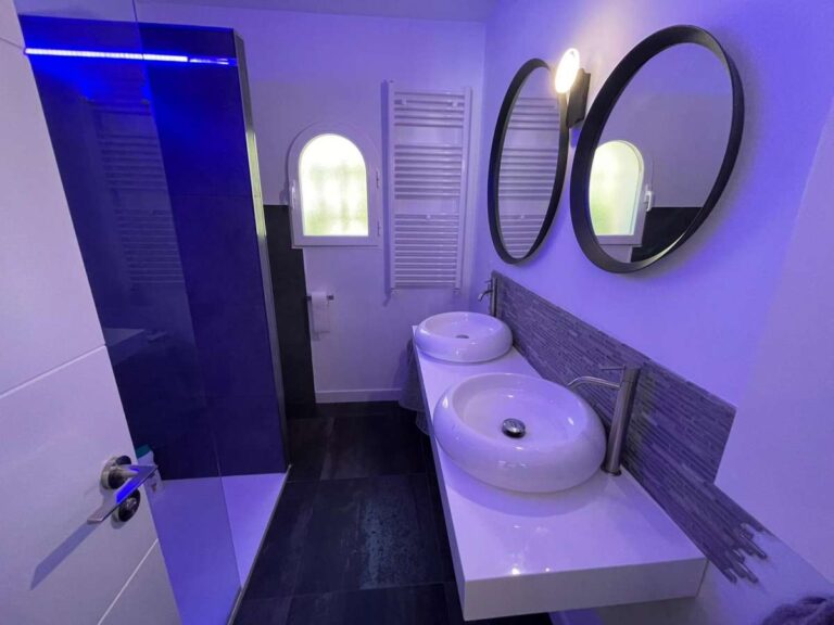 Bathroom with double round mirrors, basin and walk-in shower inside a refurbished villa in Canuta, Calpe.
