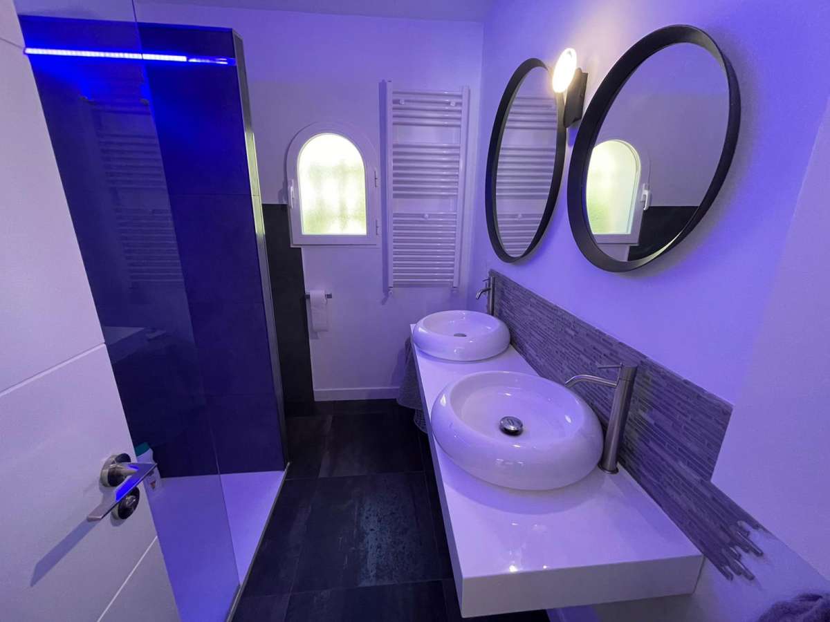 Bathroom with double round mirrors, basin and walk-in shower inside a refurbished villa in Canuta, Calpe.