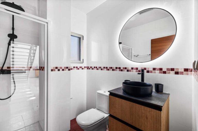 Bathroom with round mirror, vanity and shower inside a modern spacious villa in Calpe.