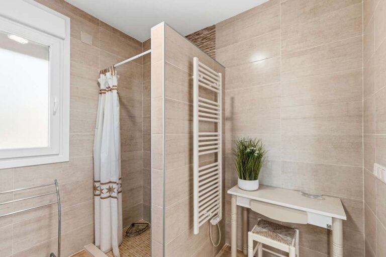 Bathroom with shower area, towel radiator and vanity inside a contemporary villa in Calpe.
