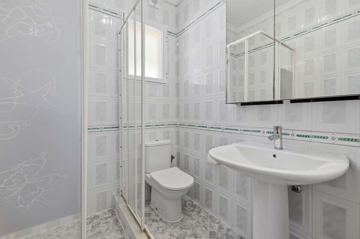Bathroom with shower, sink, toilet, and tiled walls inside a villa in Calpe.