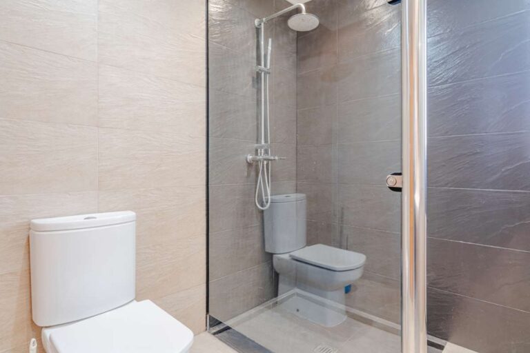Bathroom with shower, toilet and tiled walls inside a Mediterranean villa with independent guest accommodation in Calpe.