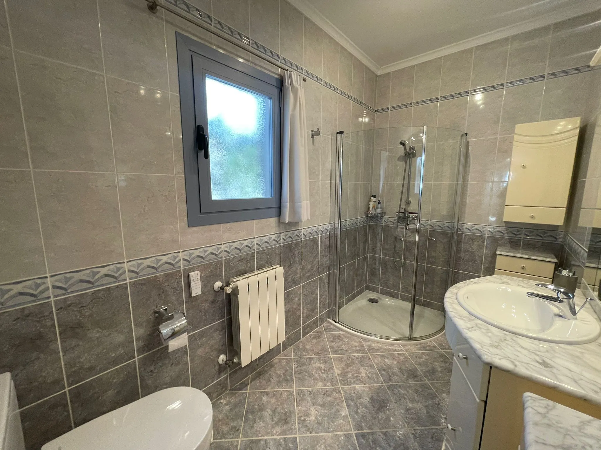 Bathroom with shower, vanity, and radiator inside a villa in Calpe.