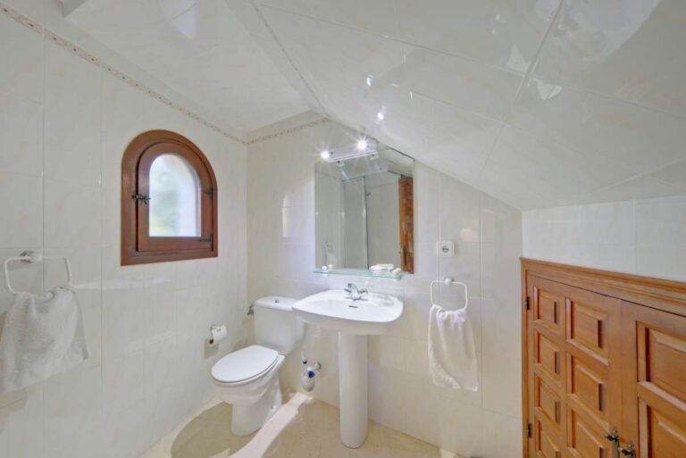 Bathroom with shower, vanity, toilet and arched window inside a second line Mediterranean villa near Puerto Blanco in Calpe.
