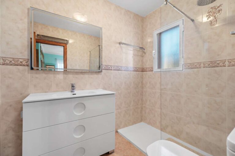 Bathroom with vanity, bath and window inside a single-level villa in Calpe close to beaches and amenities.
