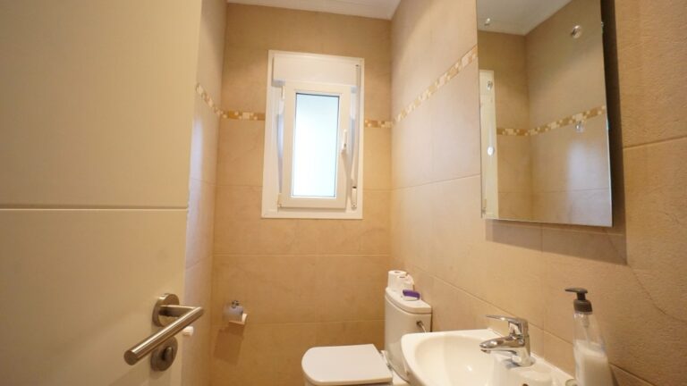 Bathroom with vanity, mirror, and natural light inside a villa near La Fustera beach.