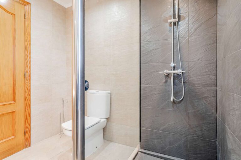 Bathroom with walk-in shower, toilet and tiled walls inside a Mediterranean villa with independent guest accommodation in Calpe.