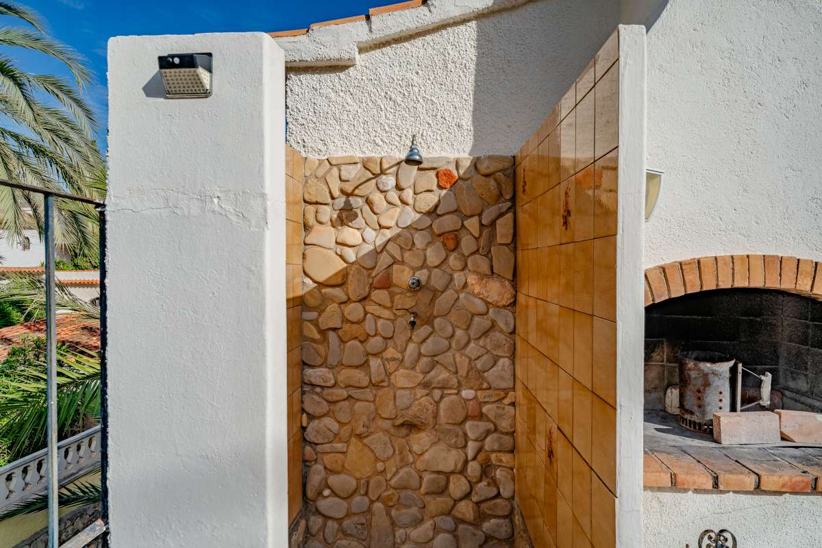 BBQ area with stone feature wall and covered terrace space at a Mediterranean villa in Maryvilla, Calpe.