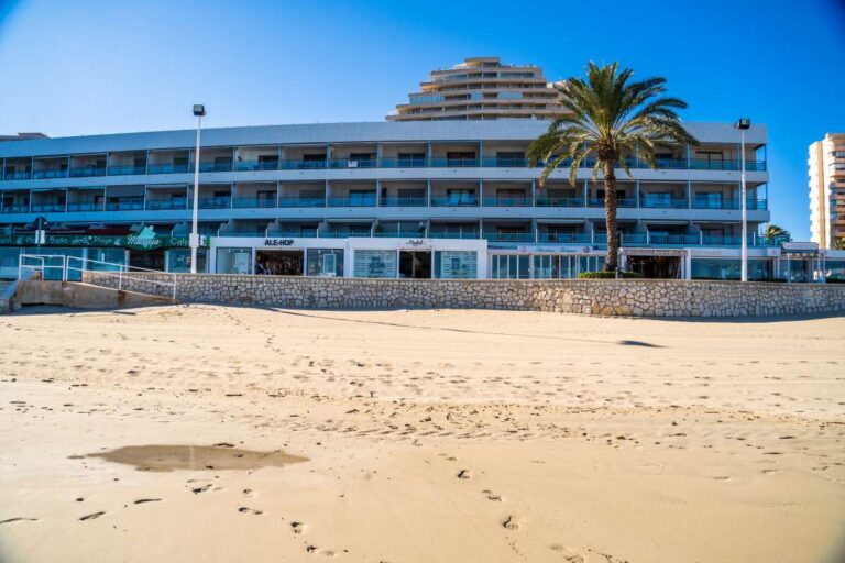 Beachfront apartment building by La Fossa Beach in Calpe viewed from the sand with promenade access and Mediterranean setting