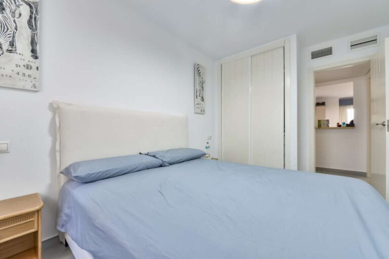 Bedroom inside a beachfront apartment in La Fossa, Calpe with fitted wardrobe, natural light and access towards the living area